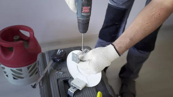 Un hombre taladra una superficie metálica con un taladro, primer plano. — Foto de Stock