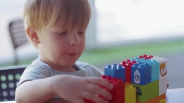 Renkli plastik bir arabayla oynayan küçük sevimli bir çocuğun yakın çekimi..