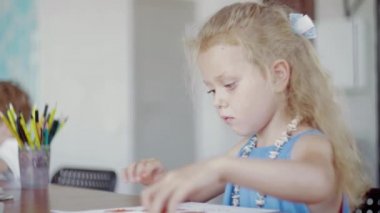 Bir kız masada renkli plastikle oynuyor.