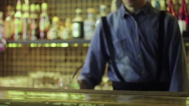 Barmen bir bardak getirdi, alkollü bir kokteyl, ve tezgahın üzerine koydu. Yakın plan.