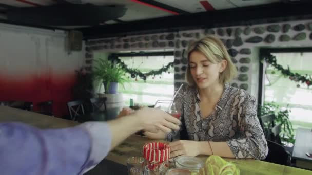 Une fille est assise dans un bar avec un verre de vin dans les mains et communique avec le barman — Video