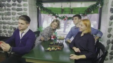 Bir grup arkadaş barda bir masaya oturup telefonda fotoğraf çekiyorlar..