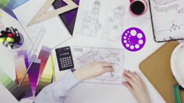 Yaratıcı bir atölyede çalışan bir cetvel üzerine çizim yapan kadın tasarımcının üst görünümü