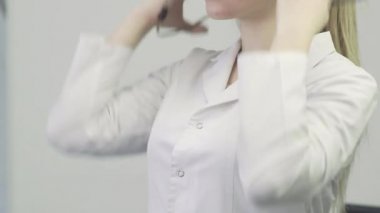 Doktorun yakın plan fotoğrafı. Tıbbi önlüklü bir kadın boynuna steteskop takıyor.