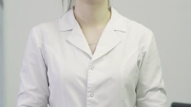 Primer plano de un médico una mujer con una bata médica se pone un estetoscopio en el cuello — Vídeos de Stock