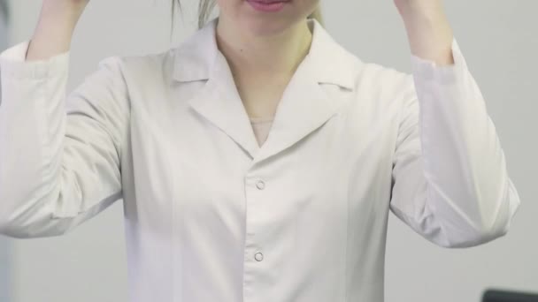 Close-up of a doctor a woman in a medical gown puts a stethoscope on her neck — Stock Video