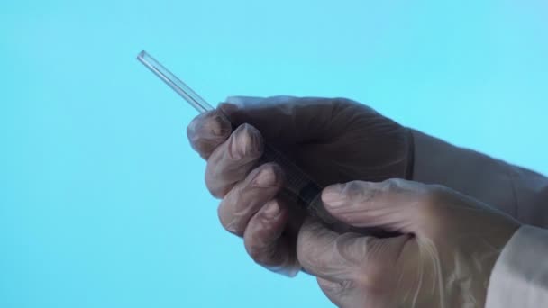 Gros plan d'une aiguille d'une seringue jetable. Une petite seringue pousse le liquide hors du trou sur un fond bleu — Video