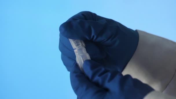 파란 배경에 있는 백신의 플라스틱 암 굴을 여는 라텍스 장갑을 낀 손의 근접 사진 — 비디오