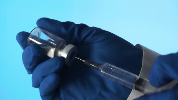 Doktorun elleri mavi arka planda aşı için aşı hazırlıyor. — Stok video