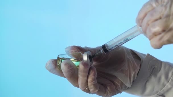 Großaufnahme einer Arzthand bei der Vorbereitung eines Impfstoffes für die Injektion auf blauem Hintergrund — Stockvideo