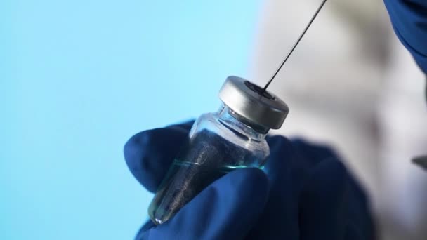 Close-up van een arts die een vaccin maakt voor injectie op een blauwe achtergrond — Stockvideo