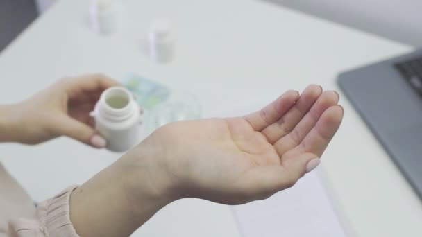 Крупним планом невпізнавана жінка, пацієнтка, тримає банку таблеток і вливає її в її руку — стокове відео