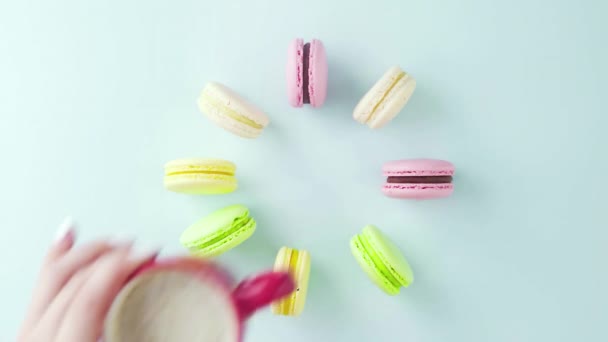 Vista superior de galletas de macarrones franceses multicolores y una taza de café sobre un fondo azul pastel — Vídeo de stock