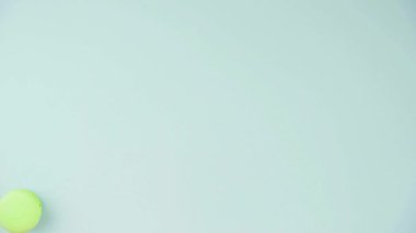 Pastel mavi arka planda çok renkli Fransız makarnalı kurabiyelerin üst görüntüsü. Bir kadın eli kurabiye serer.