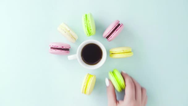 Vue de dessus des biscuits Macarons français multicolores et une tasse de café sur un fond bleu pastel — Video