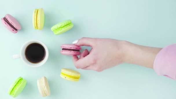 Horní pohled na pestrobarevné francouzské Macarons cookies a šálek kávy na pastelově modrém pozadí — Stock video