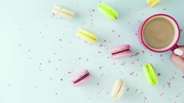 Horní pohled na barevné sušenky, francouzské Macarons, a šálek kávy na pastelově modrém pozadí s krásně rozptýlené konfety — Stock video