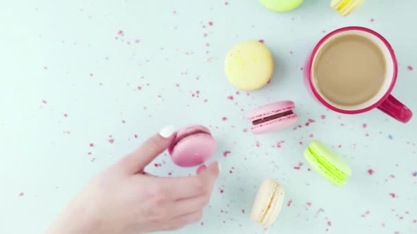 Vue de dessus de biscuits colorés, macarons français, et une tasse de café sur un fond bleu pastel avec des confettis magnifiquement dispersés — Video