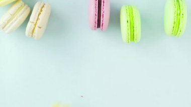 Pastel mavi arka planda çok renkli Fransız makarnalı kurabiyelerin üst görüntüsü