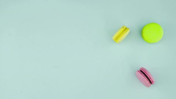 Vista superior de galletas de macarrones franceses multicolores y una taza de café sobre un fondo azul pastel — Vídeos de Stock