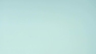 Çok renkli kurabiyelerin üst görüntüsü pastel mavi arka planda Fransız makarnaları. Bir kadının eli kurabiyeyi ortaya taşır..