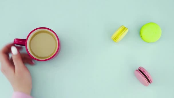 Верхній вид різнокольорових французьких печива Macarons і чашечка кави на пастельному синьому тлі. — стокове відео