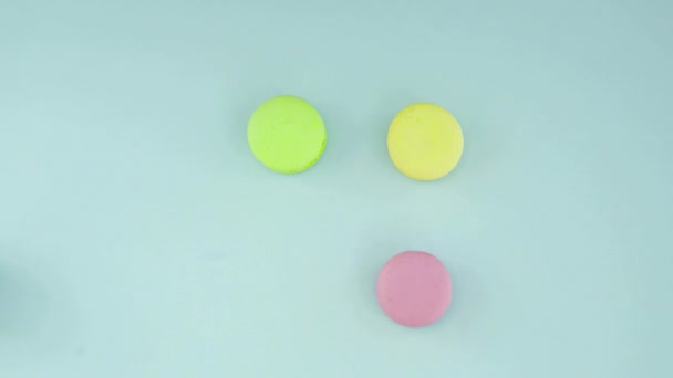 Vue de dessus des biscuits Macarons français multicolores et une tasse de café sur un fond bleu pastel — Video