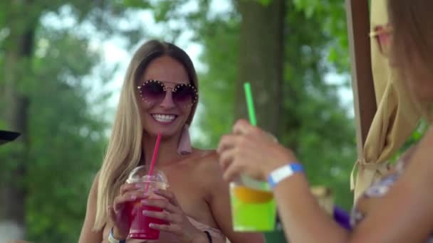 Två unga kvinnor på stranden solbadar och dricker cocktails — Stockvideo