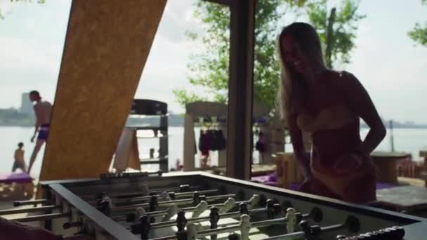 Women playing table football or kicker with miniature players on the beach in bathing suits — Stock Video