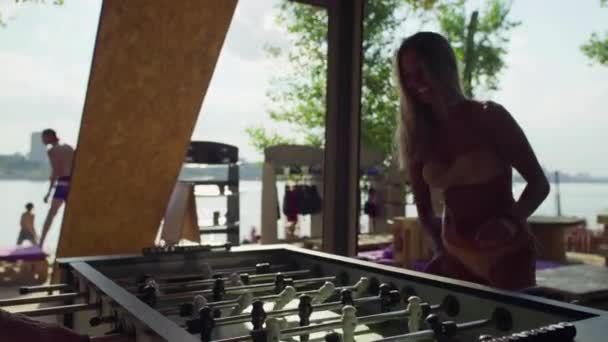 Donne che giocano a calcio balilla o kicker con giocatori in miniatura sulla spiaggia in costume da bagno — Video Stock