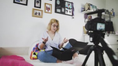 Gözlüklü genç bir kadın gülümsüyor ve kameraya yeni bir alımdan bahsediyor. Kutu açılıyor