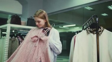 Güzel bir kız giyim mağazasında elbise deniyor. Alışveriş.