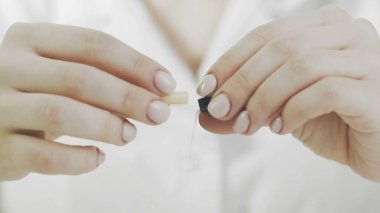 Bir kadın sarı bir tıbbi kapsül açar ve üzerine sarı toz döker.