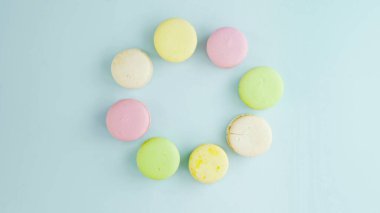 Pastel mavi arka planda renkli Fransız badem kurabiyelerinin üst görünümü