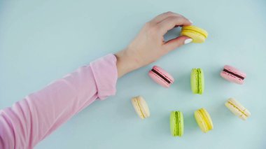 Pastel mavi arka planda renkli Fransız badem kurabiyelerinin üst görünümü