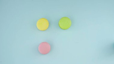 Pastel mavi arka planda renkli Fransız badem kurabiyelerinin üst görünümü