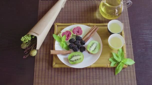 Prato de fruto delicioso em uma chapa com chá verde fragrante em uma bandeja de madeira — Vídeo de Stock