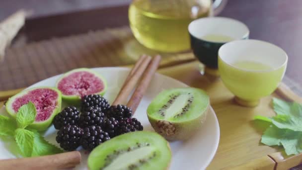 Läcker frukt skålen på en tallrik med doftande grönt te på en trälåda — Stockvideo