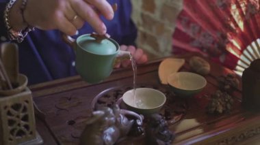 Bir adam çay bardaklarına çay koyar çay odasındaki ahşap tepside