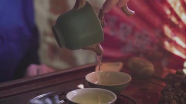 Bir adam çay bardaklarına çay koyar çay odasındaki ahşap tepside