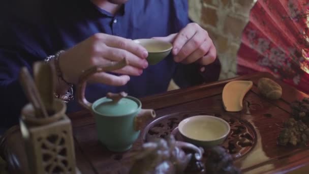 Un hombre bebe té verde de un juego de té en una sala de té — Vídeos de Stock