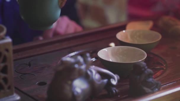 Un homme verse du thé dans des tasses à thé sur un plateau en bois dans un salon de thé — Video