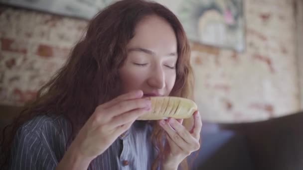 A beautiful curly-haired girl picks up a wooden bowl with tea leaves and sniffs — Stock Video