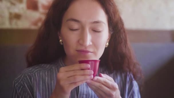Una bella ragazza dai capelli ricci assaggia il tè e gode del gusto — Video Stock