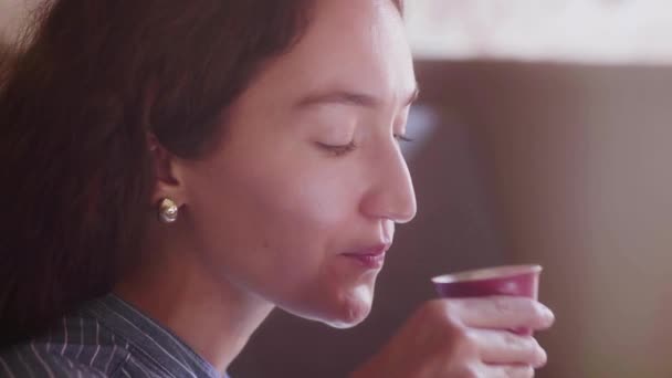 Una hermosa chica de pelo rizado prueba el té y disfruta del sabor — Vídeos de Stock