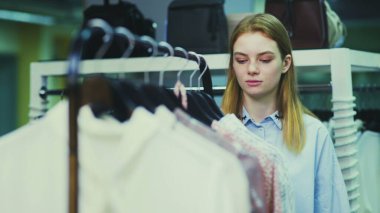 Şirin bir kız mağazadan kıyafet seçer. Alışveriş.