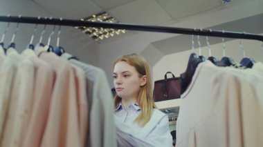 Şirin bir kız mağazadan kıyafet seçer. Alışveriş.