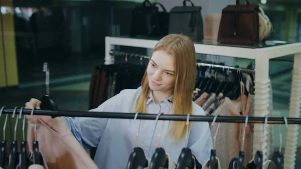 A cute girl chooses clothes in a store. Shopping — Stock Photo, Image