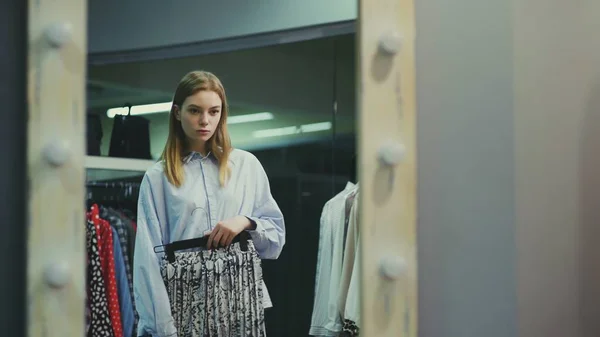 A pretty girl tries on clothes in a clothing store. Shopping — Stock Photo, Image