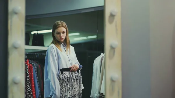 A pretty girl tries on clothes in a clothing store. Shopping — Stock Photo, Image